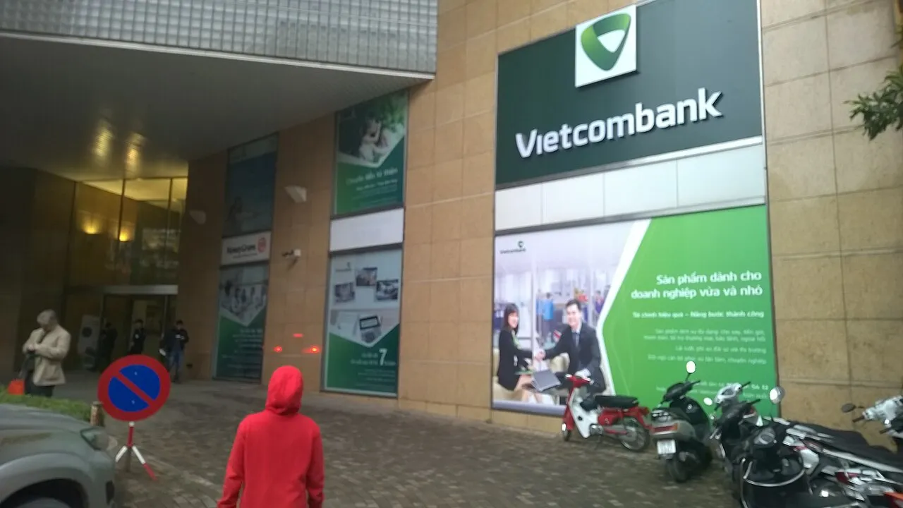Façade d'une agence Vietcombank avec son enseigne verte et des scooters garés devant