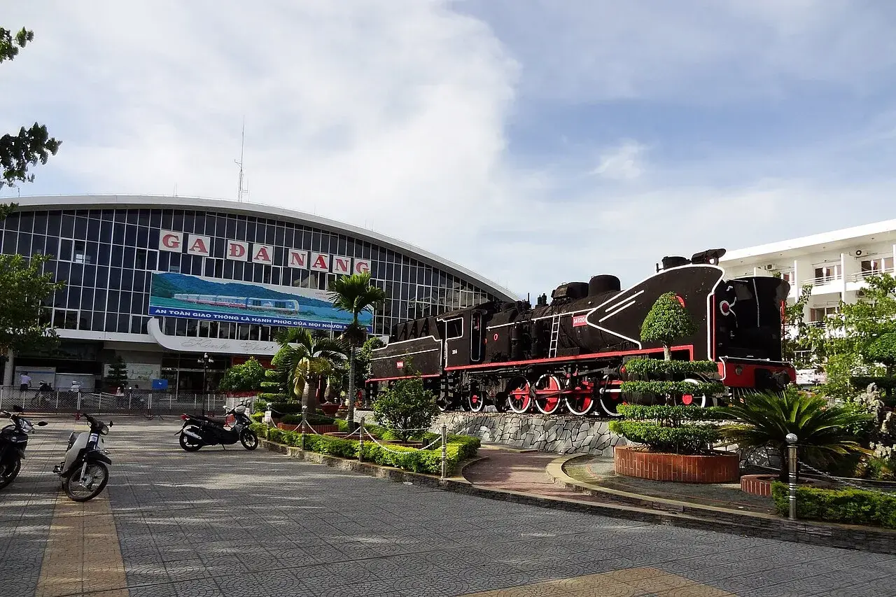 Façade de la gare de Đà Nẵng, avec l'enseigne Ga Đà Nẵng et une locomotive à vapeur exposée sur le parvis