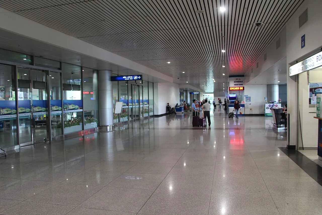 Le hall des arrivées de l'aéroport international de Tân Sơn Nhất, avec un panneau lumineux SIMCARD 3G et un bureau de change
