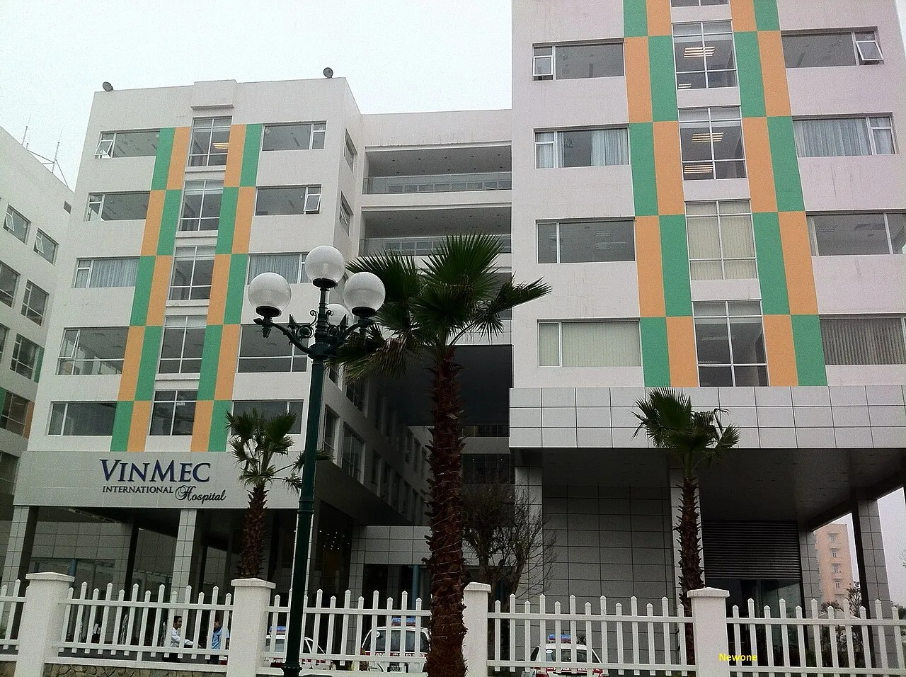Façade de l'hôpital international Vinmec à Times City, Hanoï, avec son enseigne Vinmec International Hospital, des palmiers et une clôture blanche