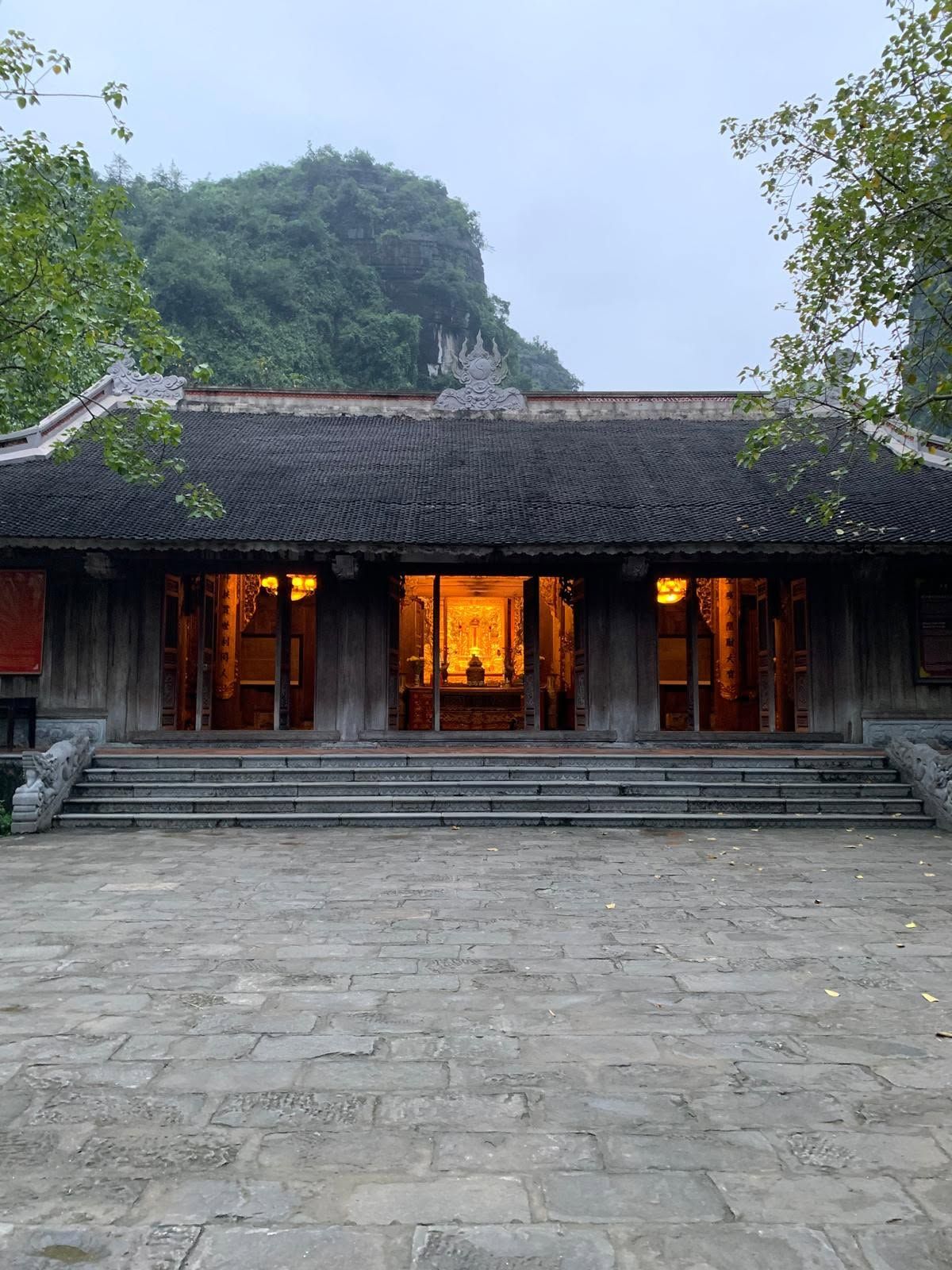 Temple en bois au pied d'un piton calcaire à Ninh Bình, intérieur éclairé à la tombée du jour