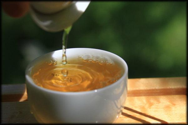 Thé doré vietnamien versé dans une tasse blanche
