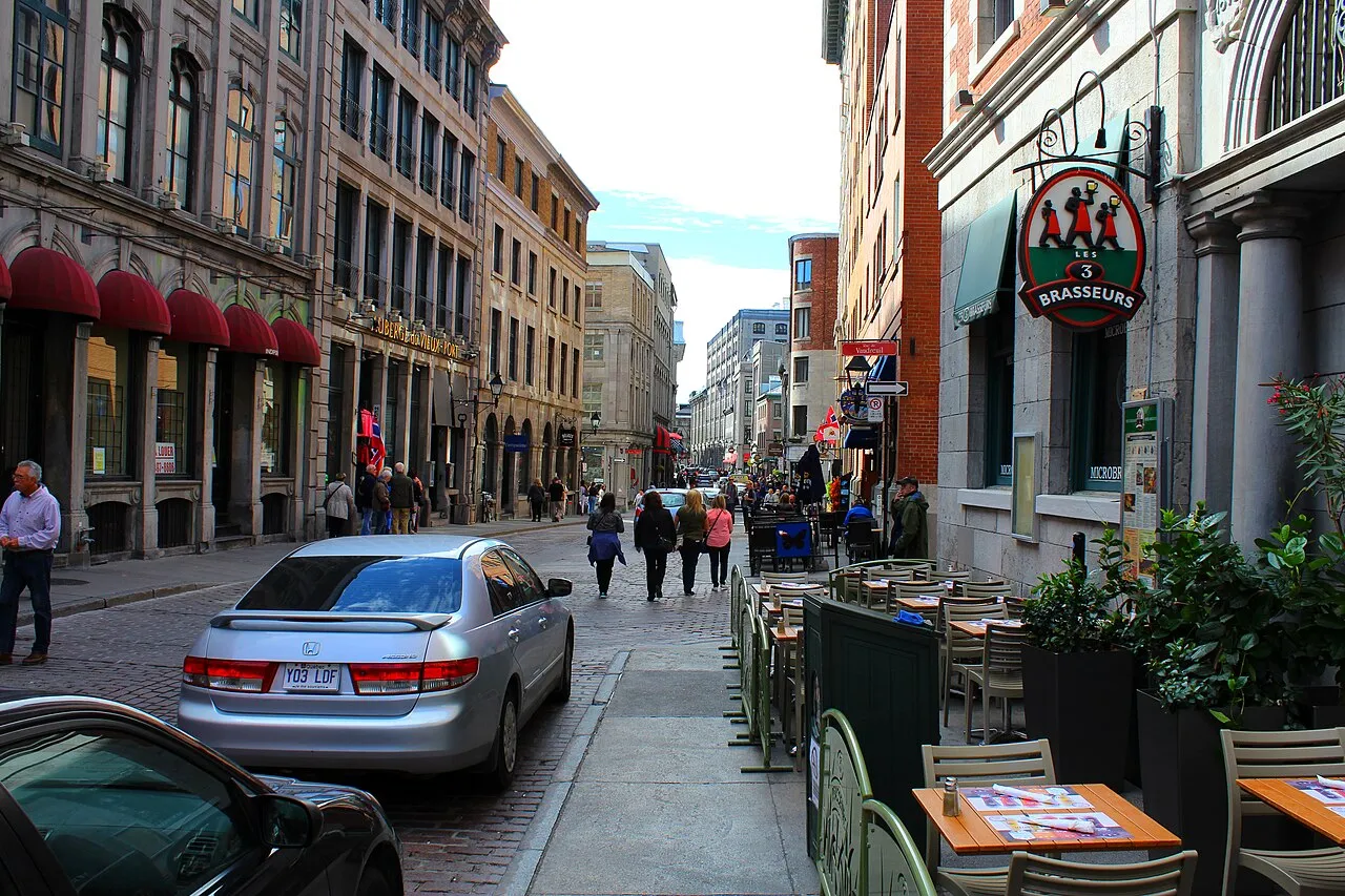 La rue Saint-Paul pavée dans le Vieux-Montréal, bordée de façades anciennes et de terrasses de restaurants, avec des passants