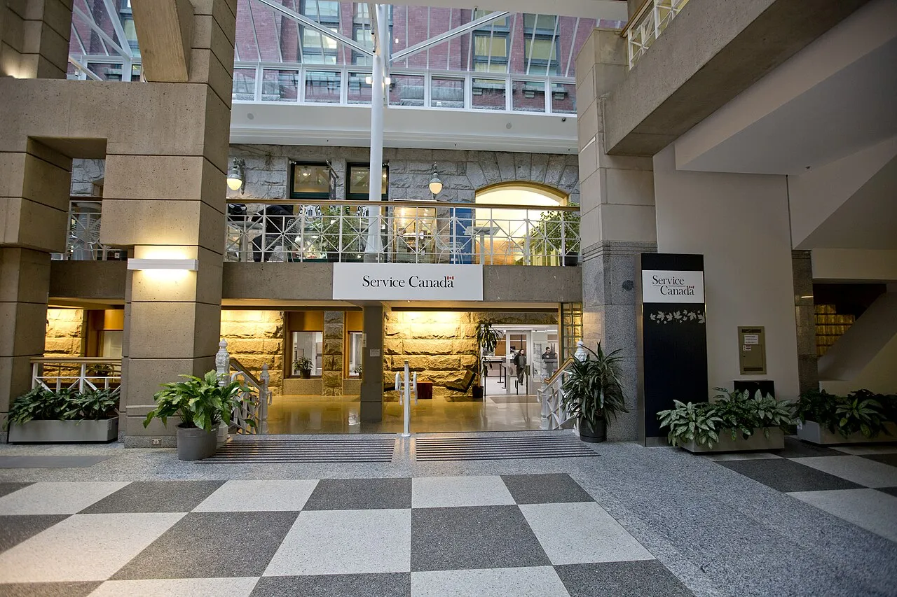 Entrée d'un bureau Service Canada dans le hall du Sinclair Centre, avec l'enseigne Service Canada au-dessus du passage et des plantes en pots