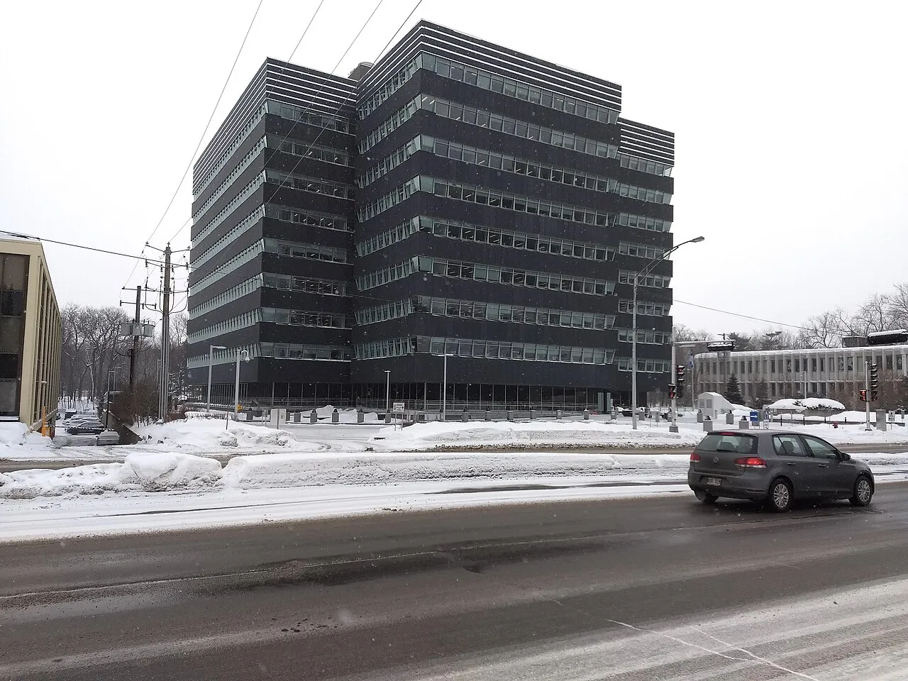 Le siège de la Régie de l'assurance maladie du Québec, un immeuble de bureaux sombre sur Grande Allée Ouest, sous la neige